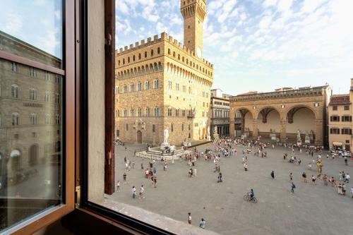 a view from a window of a city square with a clock tower at Signoria Vista by Halldis in Florence