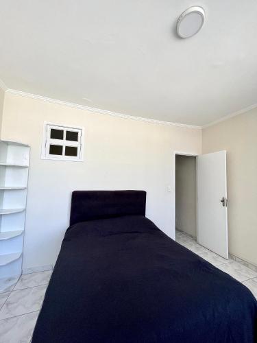a white bedroom with a bed and a window at A 1 Minuto da praia in Santos