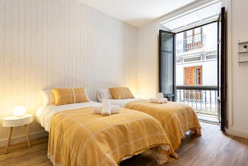 two beds in a room with a window at Casa de la Alegría Guest House in Granada