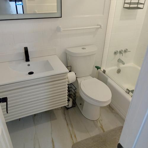 a white bathroom with a toilet and a sink at Premier Hostle in Fort Lauderdale