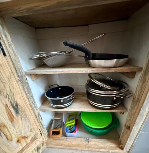 a wooden cabinet filled with pots and pans at Villa Katerina Kendwa in Kendwa