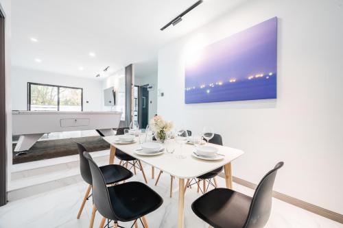 a dining room with a white table and chairs and a piano at Villa 35 Wongamart in North Pattaya