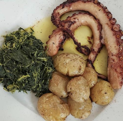 a plate of food with meat and potatoes and greens at Hotel Medieval® de Penedono in Penedono