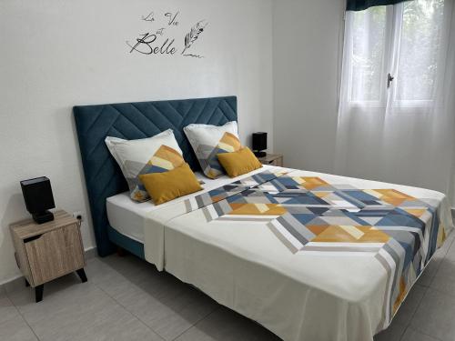 a bedroom with a large bed with yellow pillows at L'ile aux couleurs in Les Abymes
