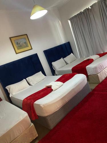a hotel room with three beds with red blankets at two lovers in Vosburg