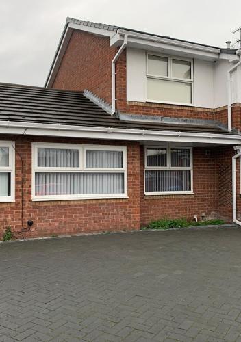 a brick house with white windows and a driveway at Chateau julie in Liverpool