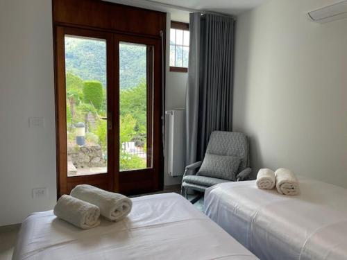 una camera con due letti e una sedia e una finestra di Villa la Grona a Menaggio