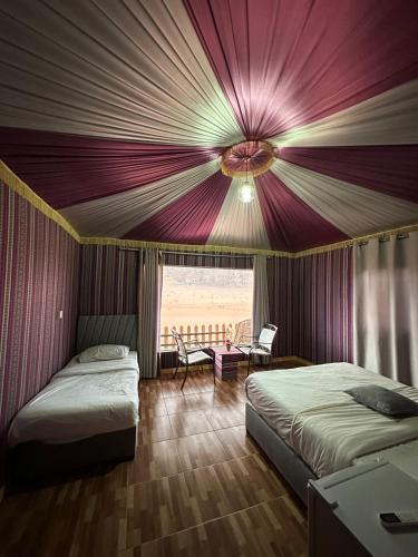 two beds in a room with a purple ceiling at Kinda Rum Luxury Camp in Wadi Rum