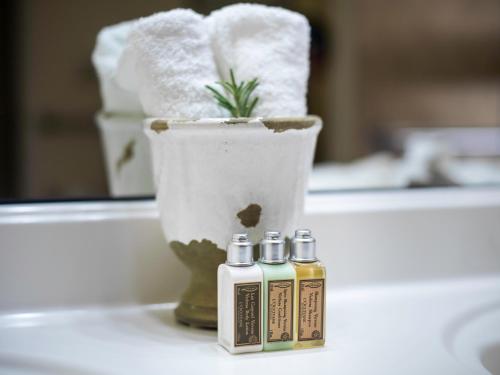 a bathroom with three bottles of essential oils and a vase at La Maison Hotel - Adults Only in Palm Springs