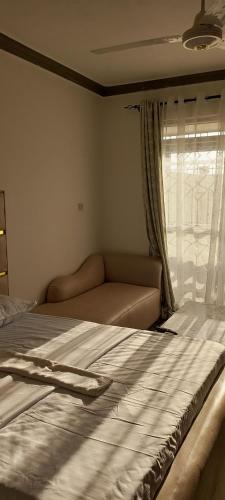 a bedroom with a bed and a window with a couch at Jnjzhomes Mombasa in Mombasa