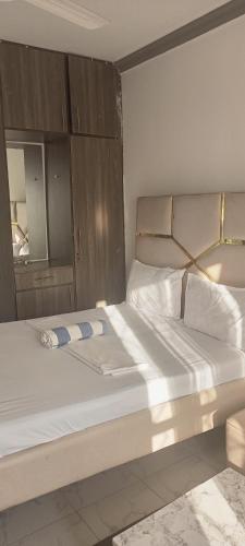 a bedroom with a large white bed with a wooden headboard at Jnjzhomes Mombasa in Mombasa