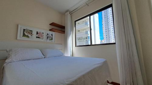 a bedroom with a white bed and a window at Centro de BC, a 200 mts da praia, garagem, churrasqueira, pet-friendly in Balneário Camboriú