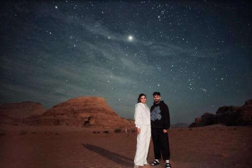 a man and a woman standing in the desert at night at Kinda Rum Luxury Camp in Wadi Rum