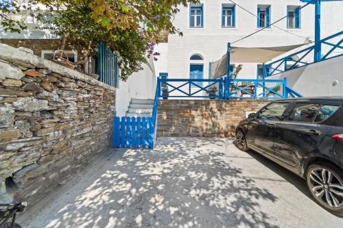 a car parked next to a stone wall with a blue gate at Aegean Beachfront Suite - Chora, Andros in Andros
