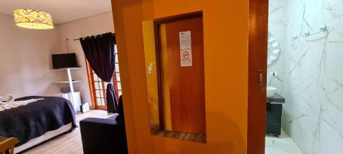 an orange door in a room with a bed at Pousada Chales da Mantiqueira - Campos do Jordão in Campos do Jordão