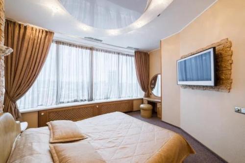 a bedroom with a bed and a tv on the wall at Апартаменты Делюкс с 1 спальней in Dnipro