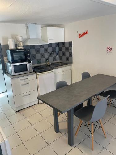 a kitchen with a table and chairs and a microwave at Les Studios de la Bastide in Carcassonne