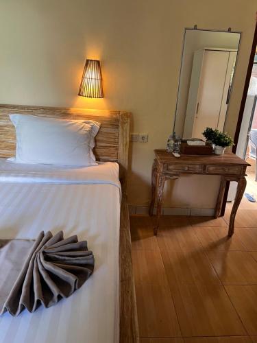 a bedroom with a bed and a table with a mirror at ADIKARA Joglo in Saba