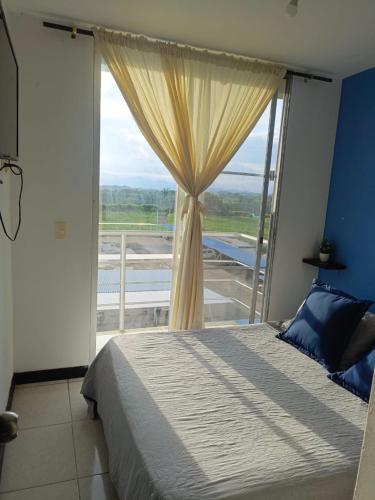 a bedroom with a bed and a large window at Lindos Apartamentos Economicos en el Eje Cafetero in Montenegro