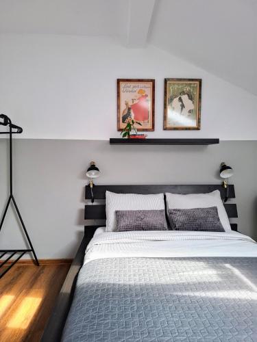 a bedroom with a bed with two pictures on the wall at Casa de pe colț in Orăştie