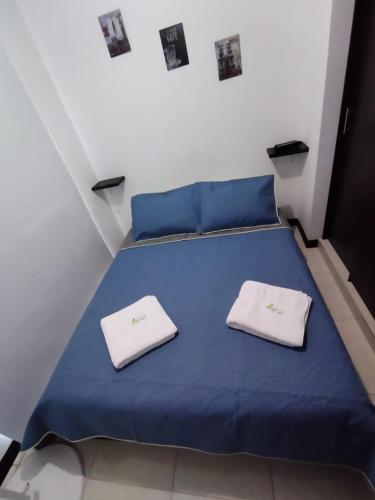 a bedroom with a blue bed with white towels on it at Lindos Apartamentos Economicos en el Eje Cafetero in Montenegro