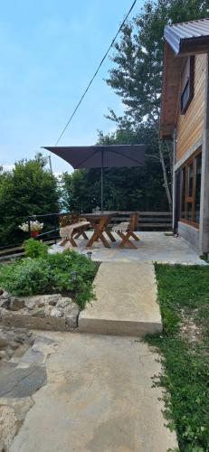 a picnic table with an umbrella next to a building at Bungalows Malagić in Gusinje