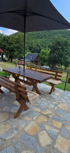 a picnic table with an umbrella on a stone ground at Bungalows Malagić in Gusinje