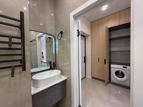 a bathroom with a sink and a washing machine at Уютная в центре города in Zhezdi