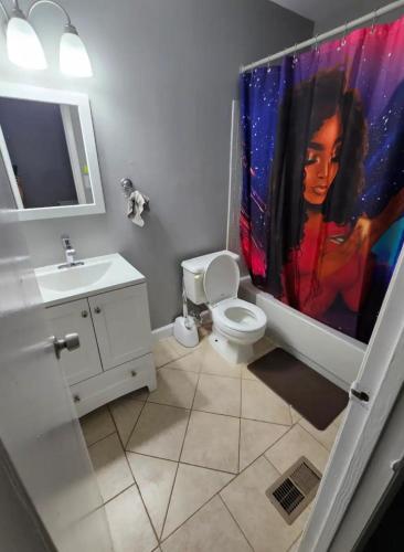a bathroom with a painting of a woman on the shower curtain at Cozy place! in Baltimore