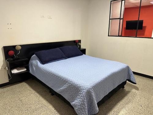 a bedroom with a bed with blue sheets and a window at Apartamentos FM 206 in Líbano