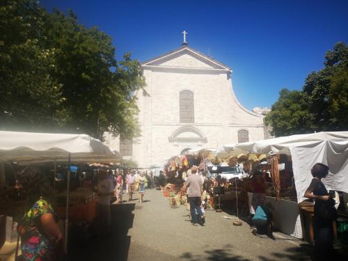 a group of people walking around an outdoor market in front of a church at Une chambre au jardin in Saint-Pons-de-Thomières