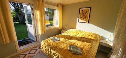 a bedroom with a bed with a yellow comforter and a window at Marias Guesthouse in Tromsø