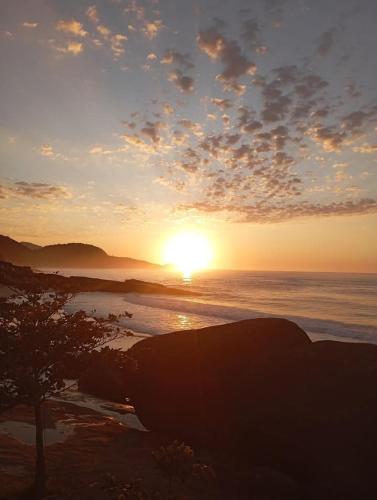 a sunset on a beach with the sun setting over the ocean at Recanto Marina in Paraty