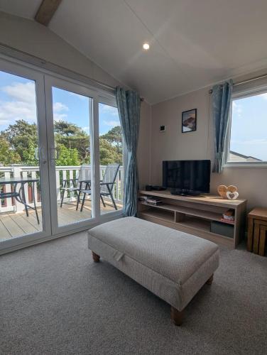 a living room with a television and a balcony at Modern Spacious Willerby Malton Caravan at Durdle Door Holiday Park, Close to Iconic Durdle Door & Lulworth Cove in West Lulworth