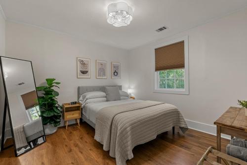 ein weißes Schlafzimmer mit einem Bett und einem Spiegel in der Unterkunft Pinky's Palace Cozy Bungalow in Port Royal