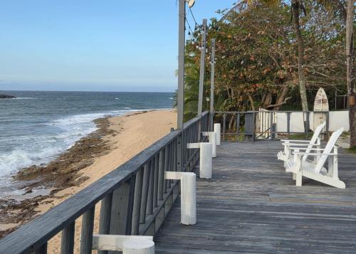 a wooden pier with white benches on the beach at Ventana Va102b at Arecibo 681 Ocean Drive in Arecibo