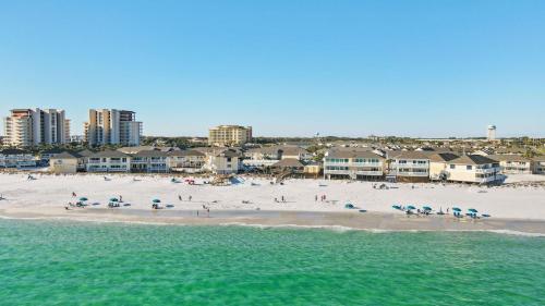 a beach with people and umbrellas in the water at Sandpiper Cove 8140 - 500 Feet to the Beach! Pool in the Back Yard! in Destin