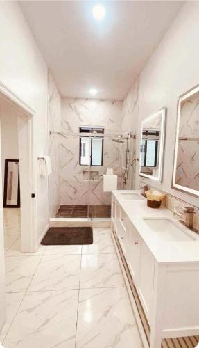 a white bathroom with two sinks and a shower at Blanco Oasis in Banks