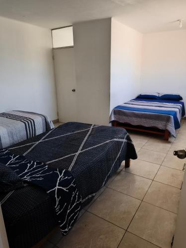 a bedroom with two beds and a tiled floor at Minidepartamento en el centro de Tacna in Tacna