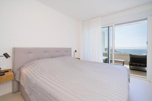 a white bedroom with a bed and a view of the ocean at La Vila - Bolnou Seaviews in Villajoyosa