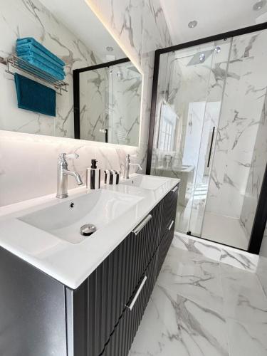 a white bathroom with a sink and a shower at Luxe Capitole122m2, Jacuzzi, Ciné, Parking, Clim, Ascenseur in Toulouse