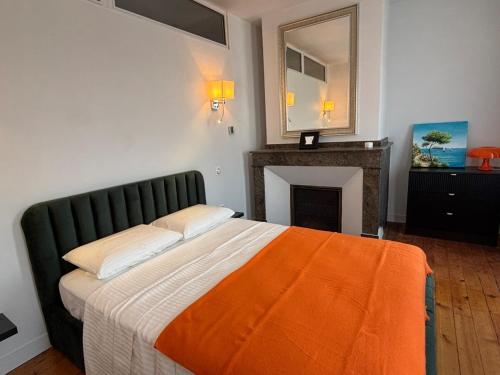 a bedroom with a bed with an orange blanket and a fireplace at Luxe Capitole122m2, Jacuzzi, Ciné, Parking, Clim, Ascenseur in Toulouse