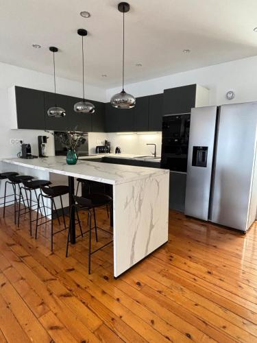 a kitchen with a large white counter and a refrigerator at Luxe Capitole122m2, Jacuzzi, Ciné, Parking, Clim, Ascenseur in Toulouse