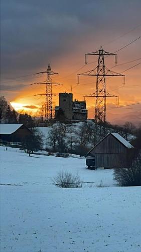 a snowy field with electricity pylons and a building at WS Ferienwohnung in Wolfurt
