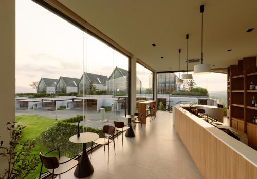a restaurant with tables and chairs and large windows at Season Hill Khao Yai in Ban Nong Song Hong