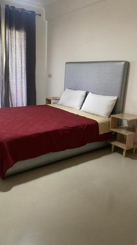 a bedroom with a bed with a red blanket and a window at Bel appartement dans un complexe prestigieux Marina Golf in Asilah