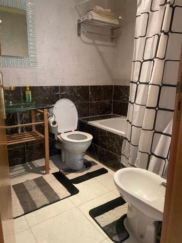 a bathroom with a toilet and a tub and a sink at Bel appartement dans un complexe prestigieux Marina Golf in Asilah
