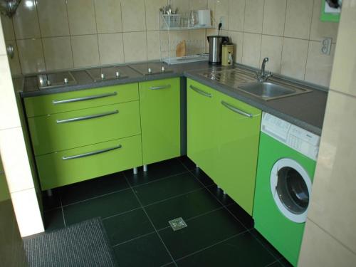 a green kitchen with a sink and a washing machine at Family Baltic Getaway in Cisowo