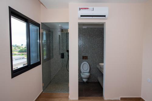 łazienka z toaletą i prysznicem z oknem w obiekcie Maison Paraíso, apartamento de lujo 1Hab w mieście Ciudad de Malabo