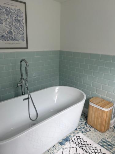 a bath tub in a bathroom with green tiles at Looe Holiday Home in Looe